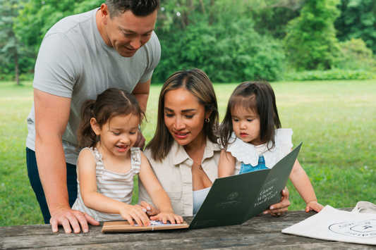 Family of four sitting at a picnic table while opening up a Guess Where Trips package.