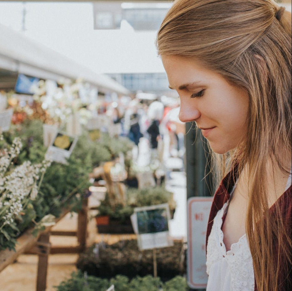 A woman browsing plants and flowers at an indoor market.