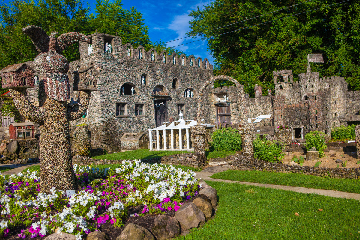 A stone castle-like building with flower gardens.