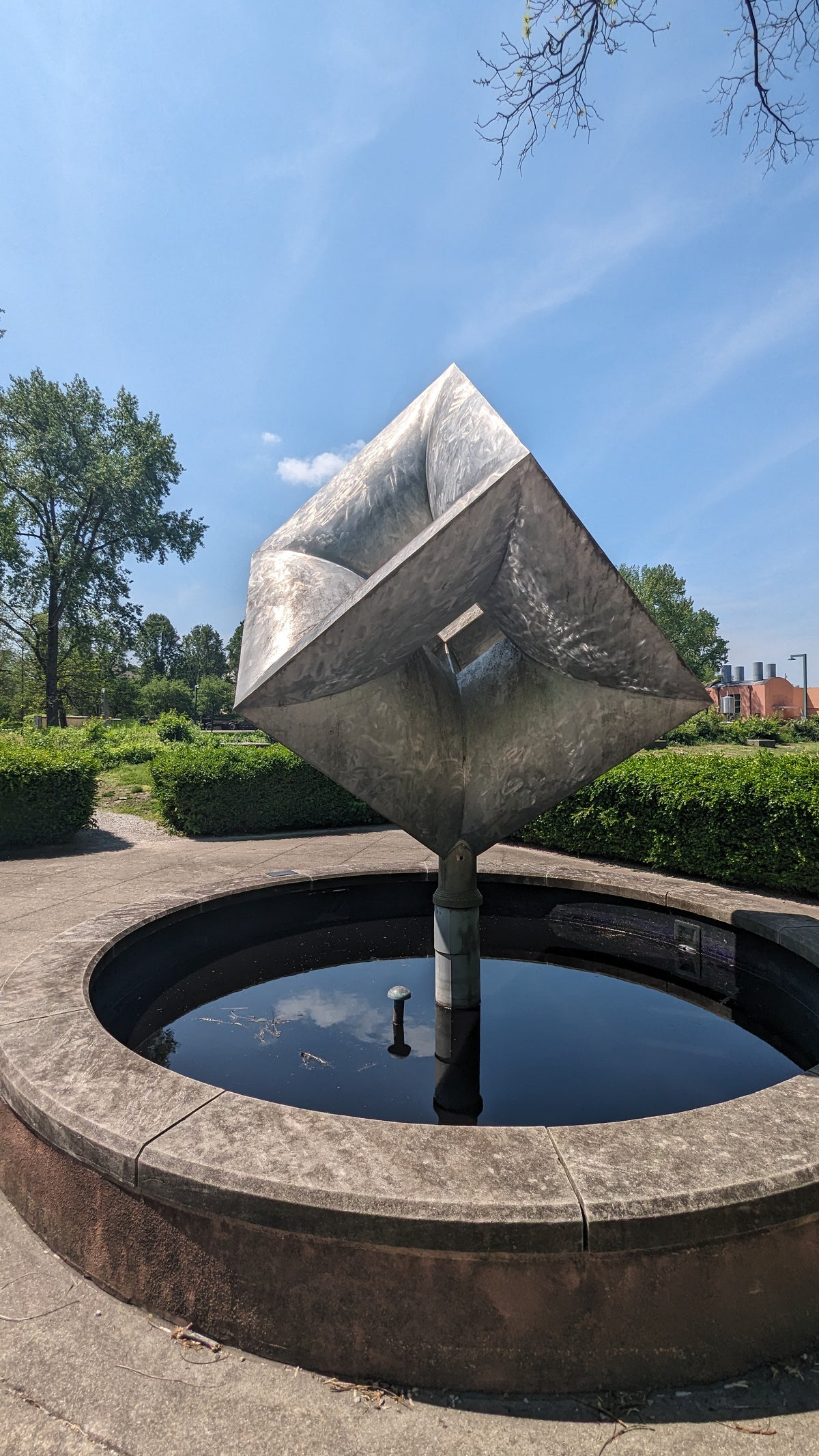 A modern sculpture above a stone fountain.