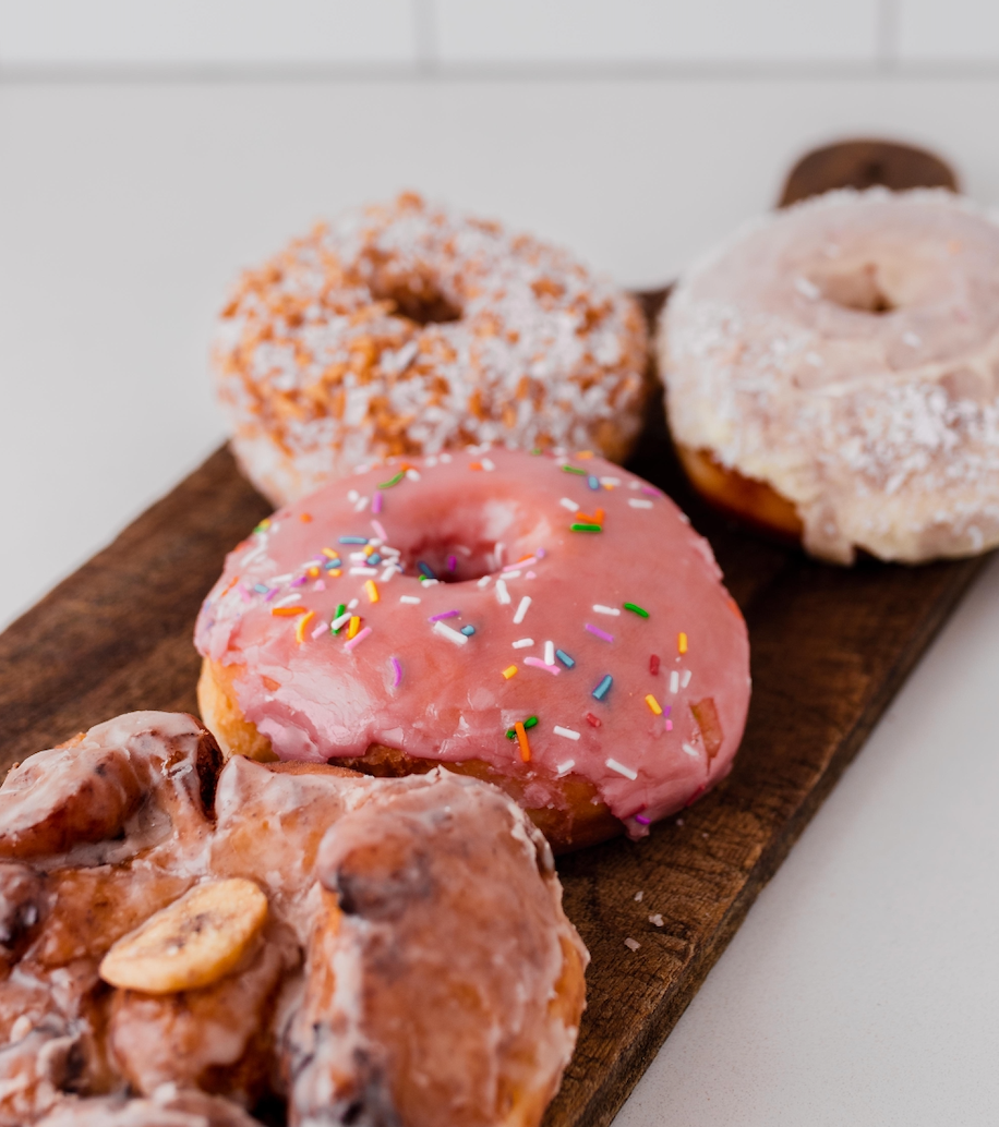 Glazed doughnuts on a wooden board.