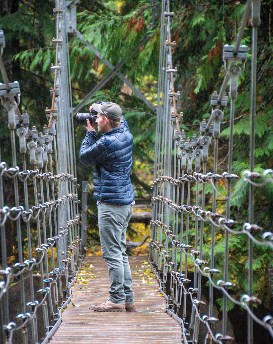 Man taking a photo from a suspension bridge.