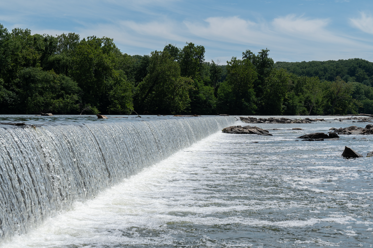 Water rushing over a wide river dam.
