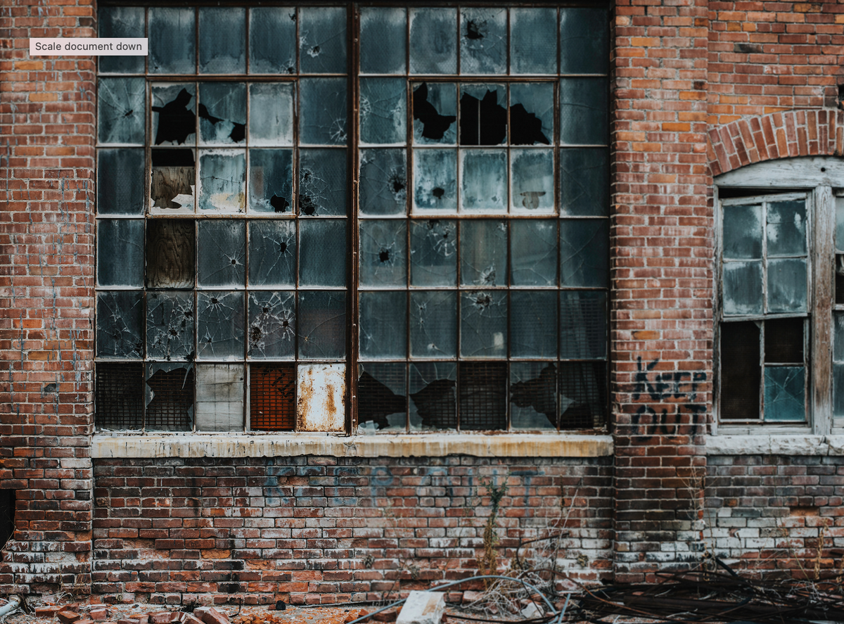 An old brick building with broken factory windows.