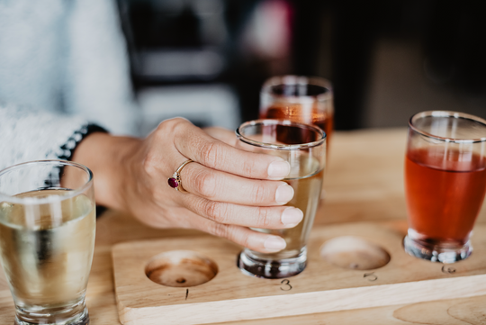 Woman picking up a beer from a flight of beer samples.