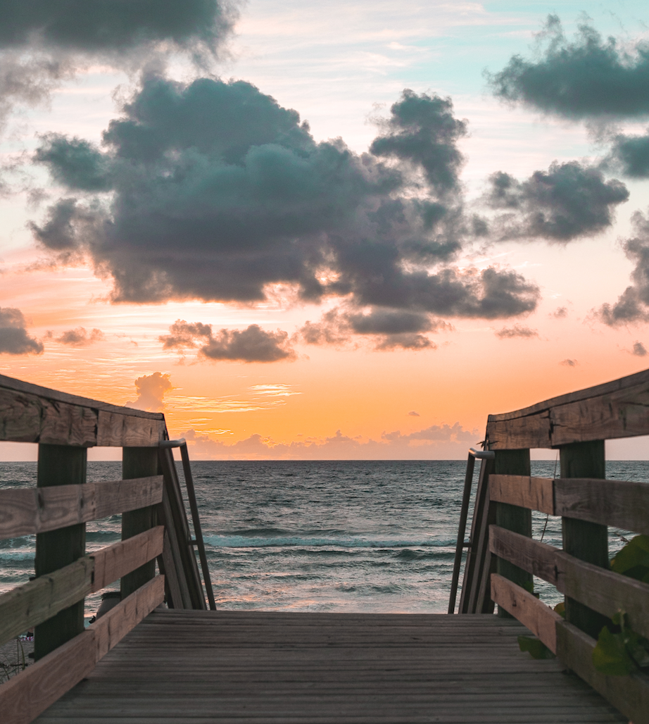 A boardwalk leading to the ocean at sunset.