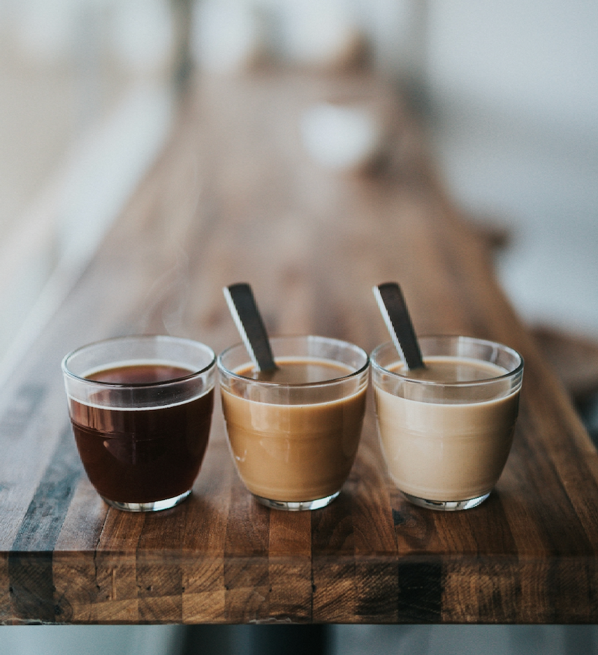 A flight of coffees on a wooden counter.