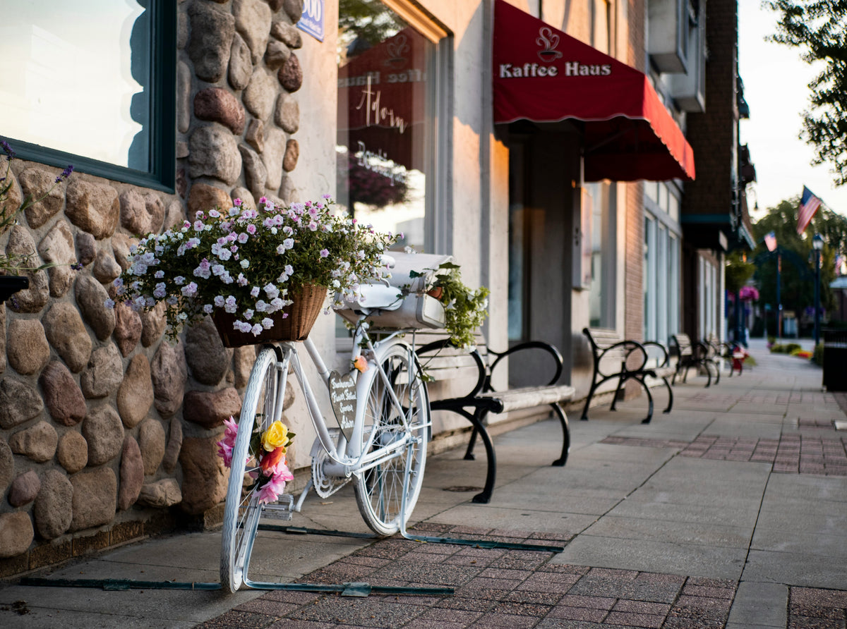 A bicycle with flowers parked on a quaint main street.