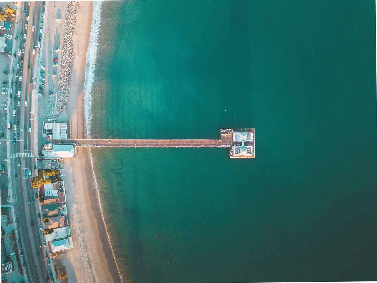 Aerial view of a pier stretching into turquoise water.