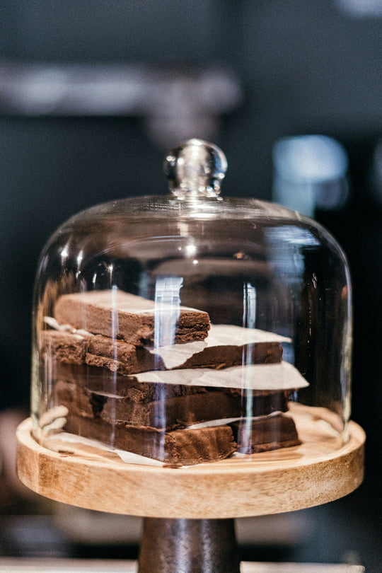 Baked goods on display on top of a cake stand with a glass lid
