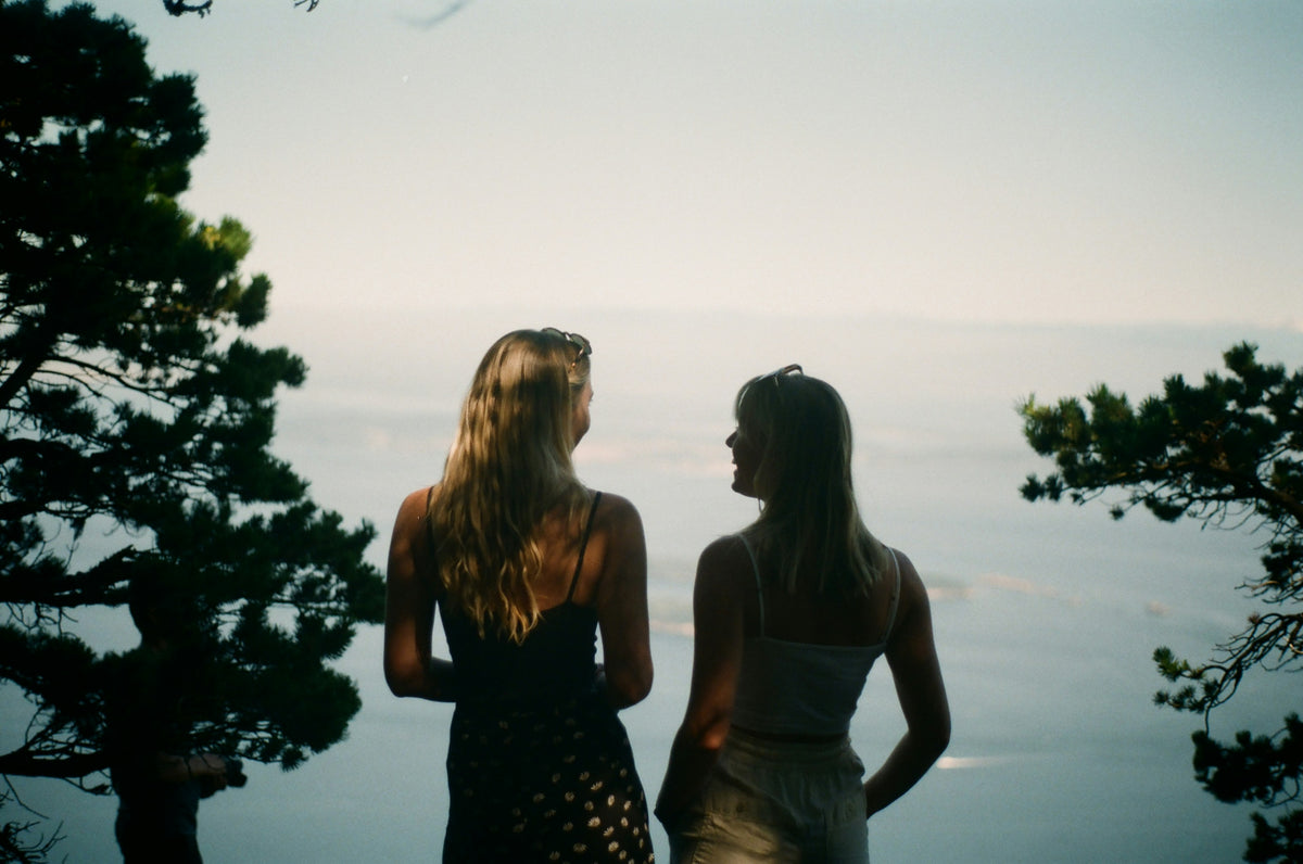 Two friends silhouetted against the water at sunset.