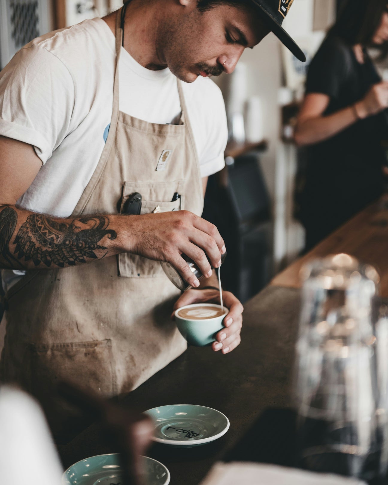 Barista behind a counter making a cappuccino.