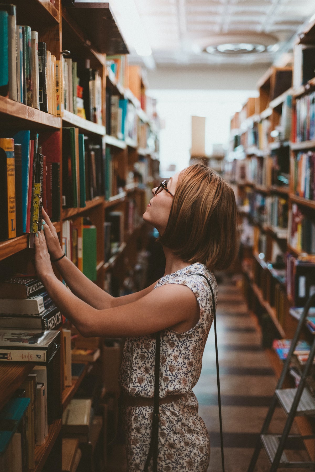 A woman browsing tall shelves in a bookstore.