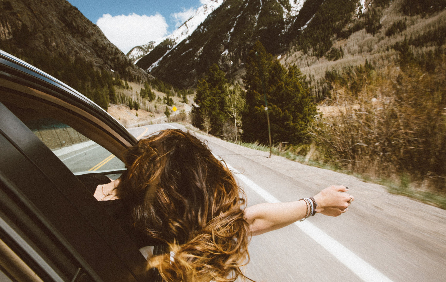 Woman on road trip leaning out window