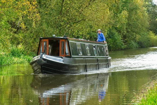 Man driving house boat along a river