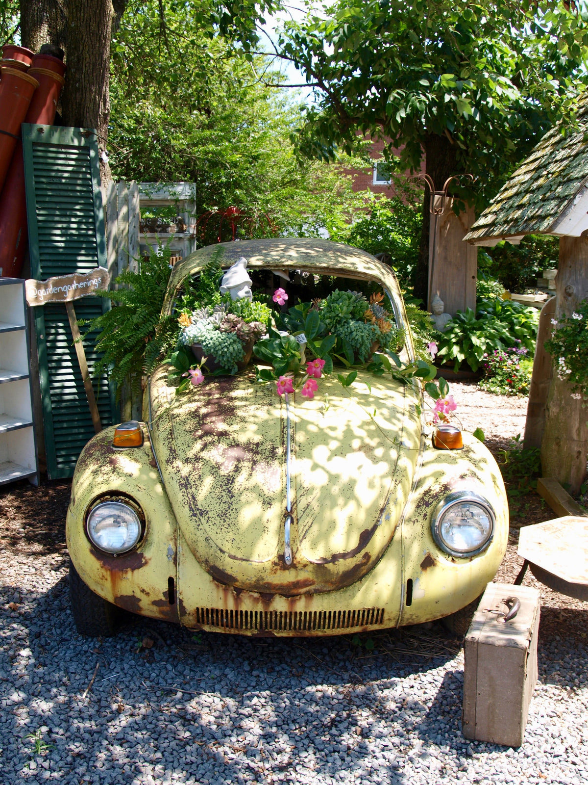 A vintage yellow Volkswagen Beetle planted with flowers.