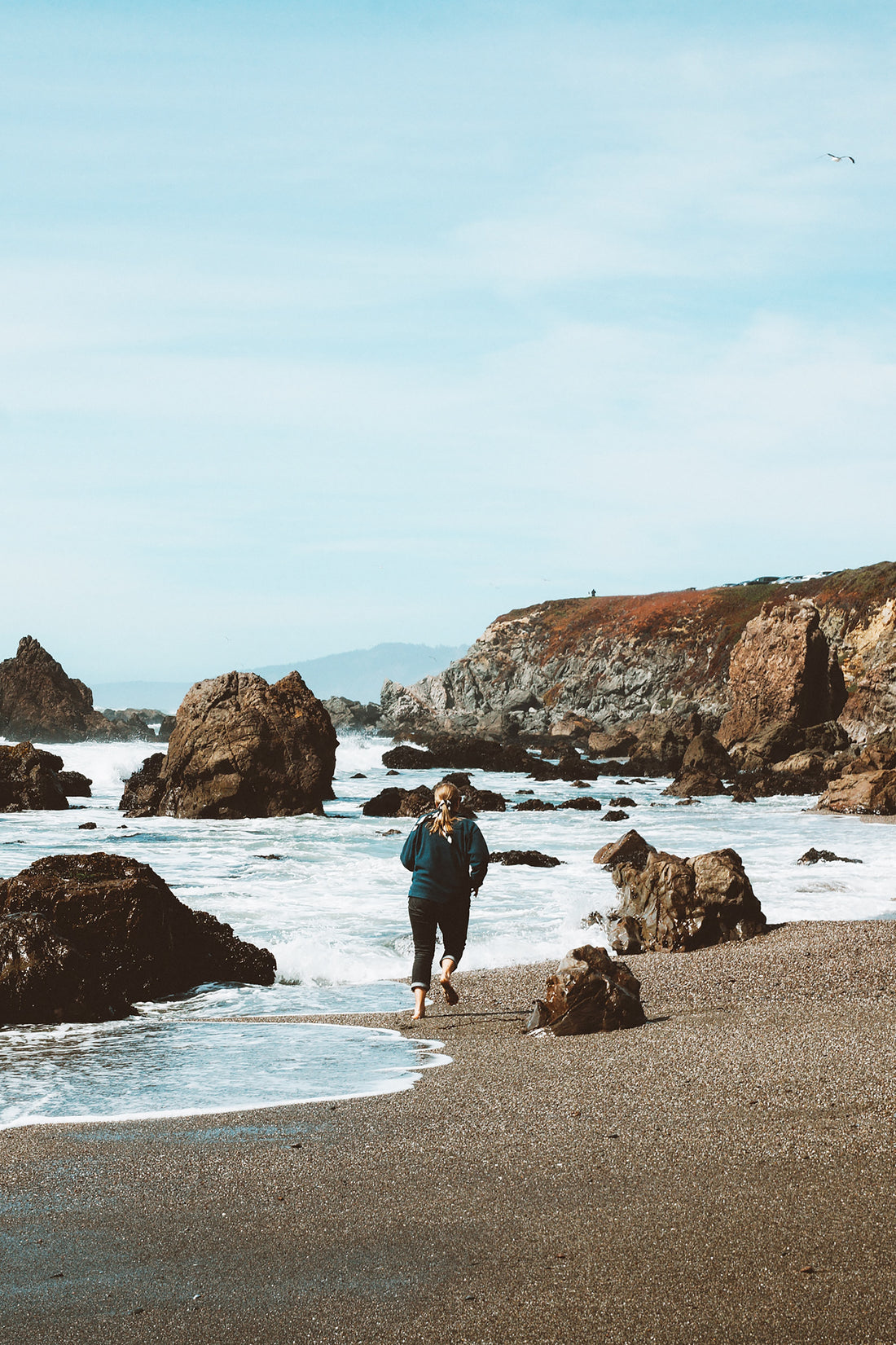 Woman running along oceanside.