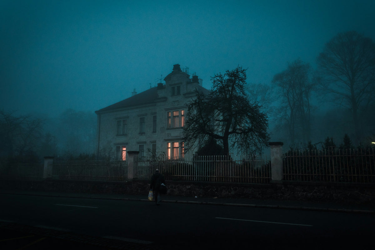A dark historic house on a foggy night.