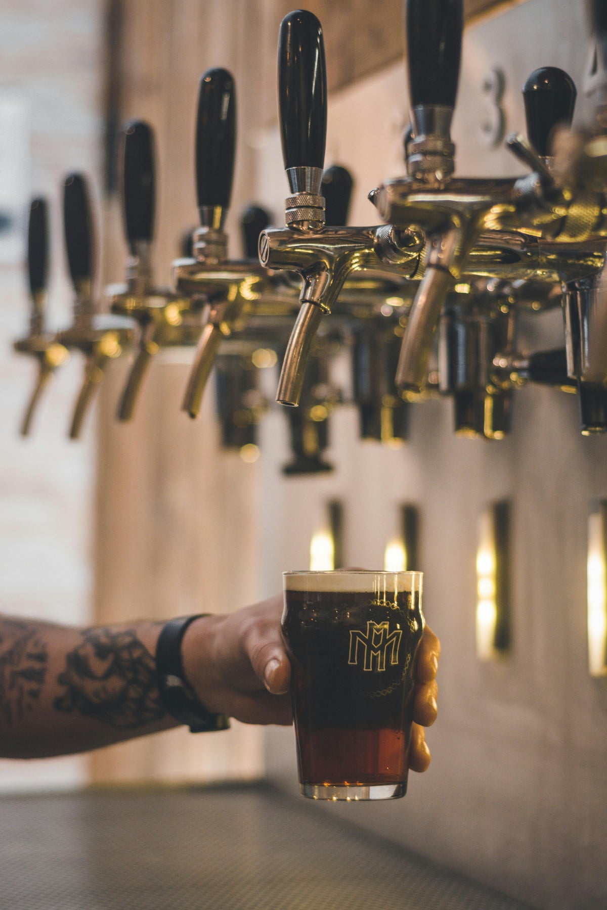 A bartender pouring a beer from a row of taps.