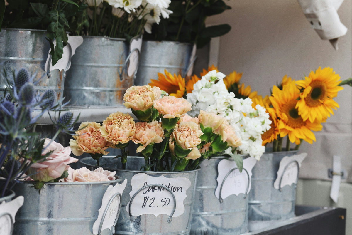 Buckets of fresh flowers at a market stall.