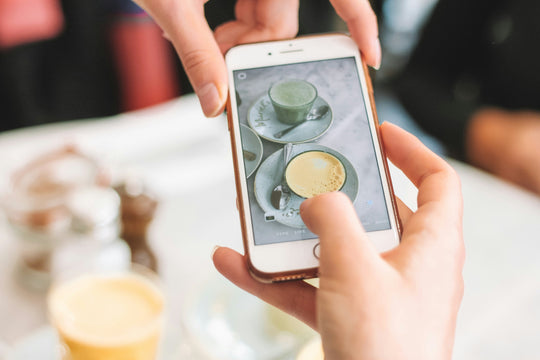 Person taking a photo of teacup on cellphone