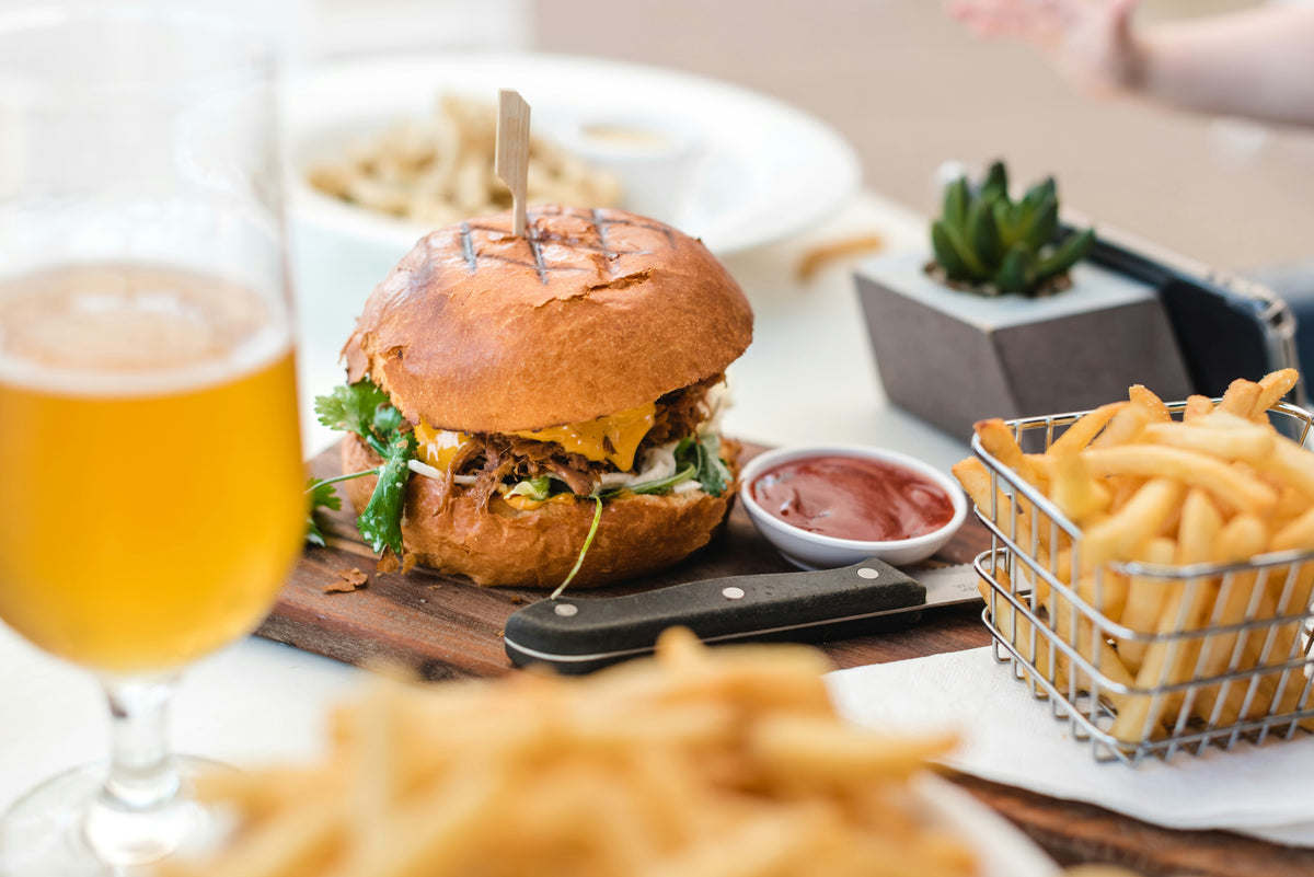 A burger, fries and a pint of beer on a restaurant table.