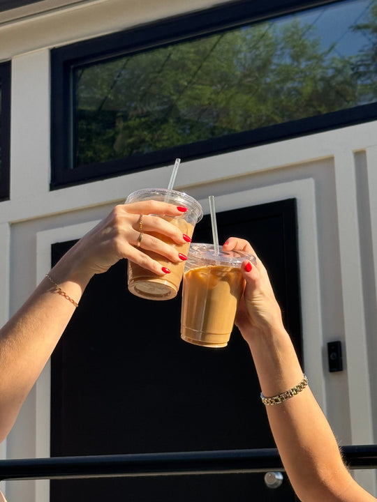 Two people saying cheers with their iced coffees.