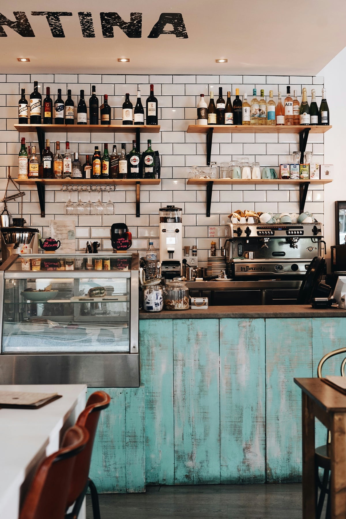 A bright café counter with shelves of bottles.