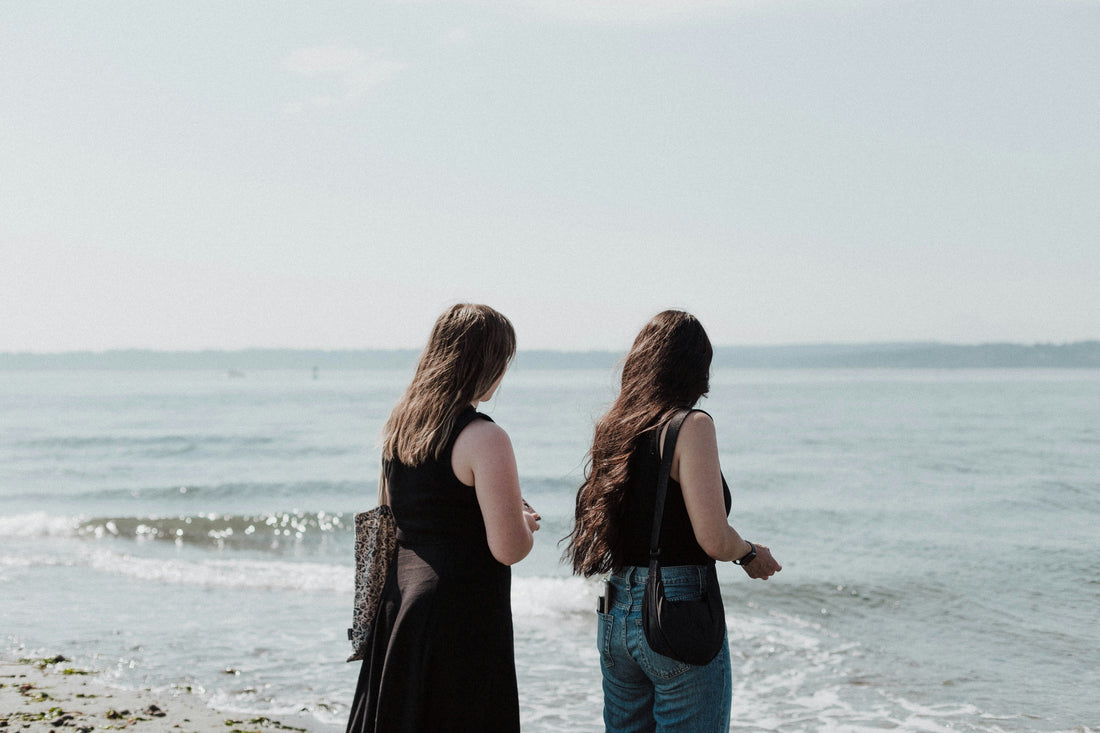 Two women on a beach looking out at the water