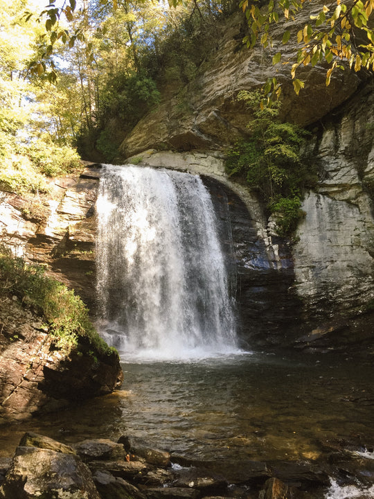 A tall waterfall cascading down a rocky cliff surrounded by greenery.