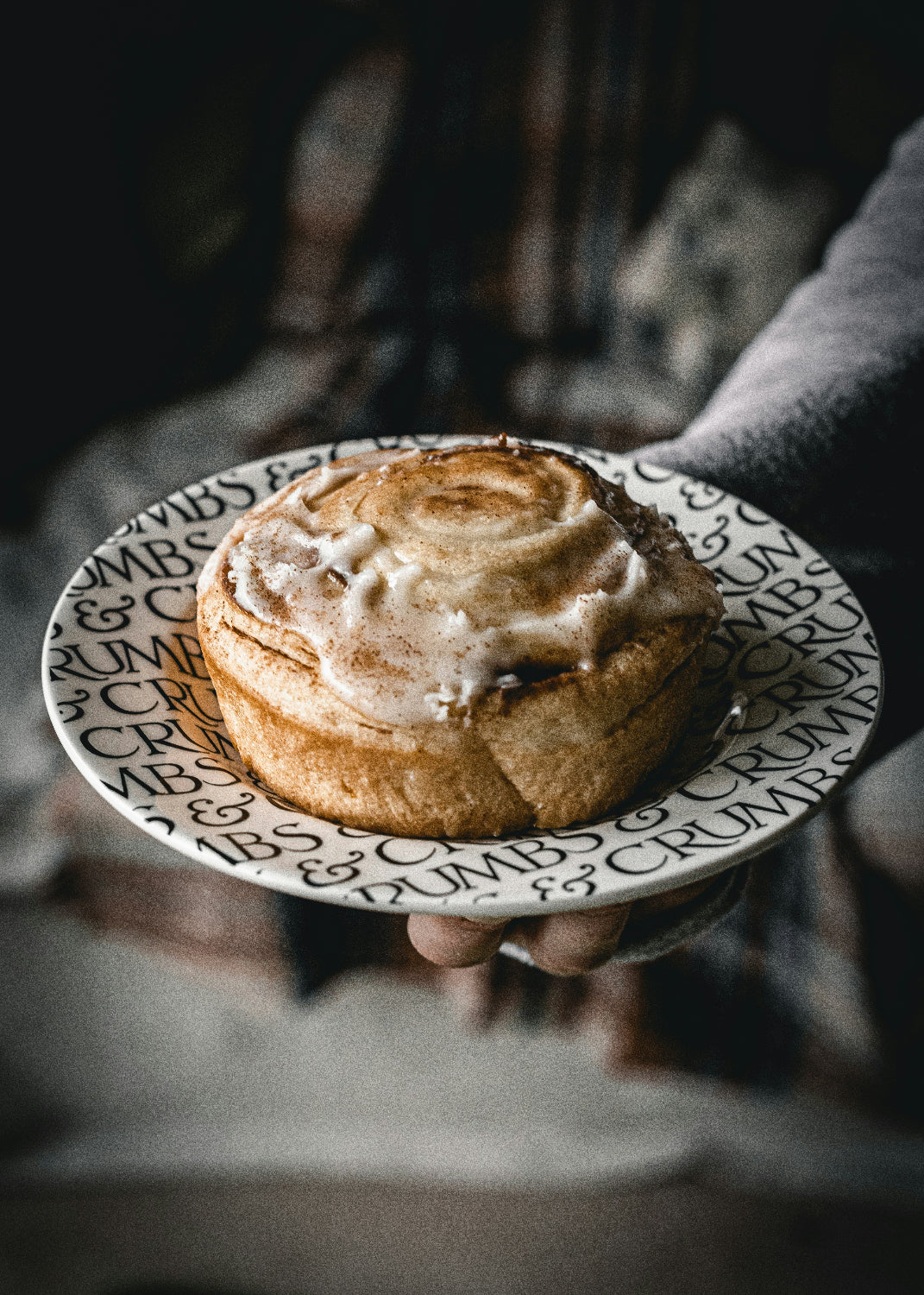 Person holding up a large cinnamon roll on a plate
