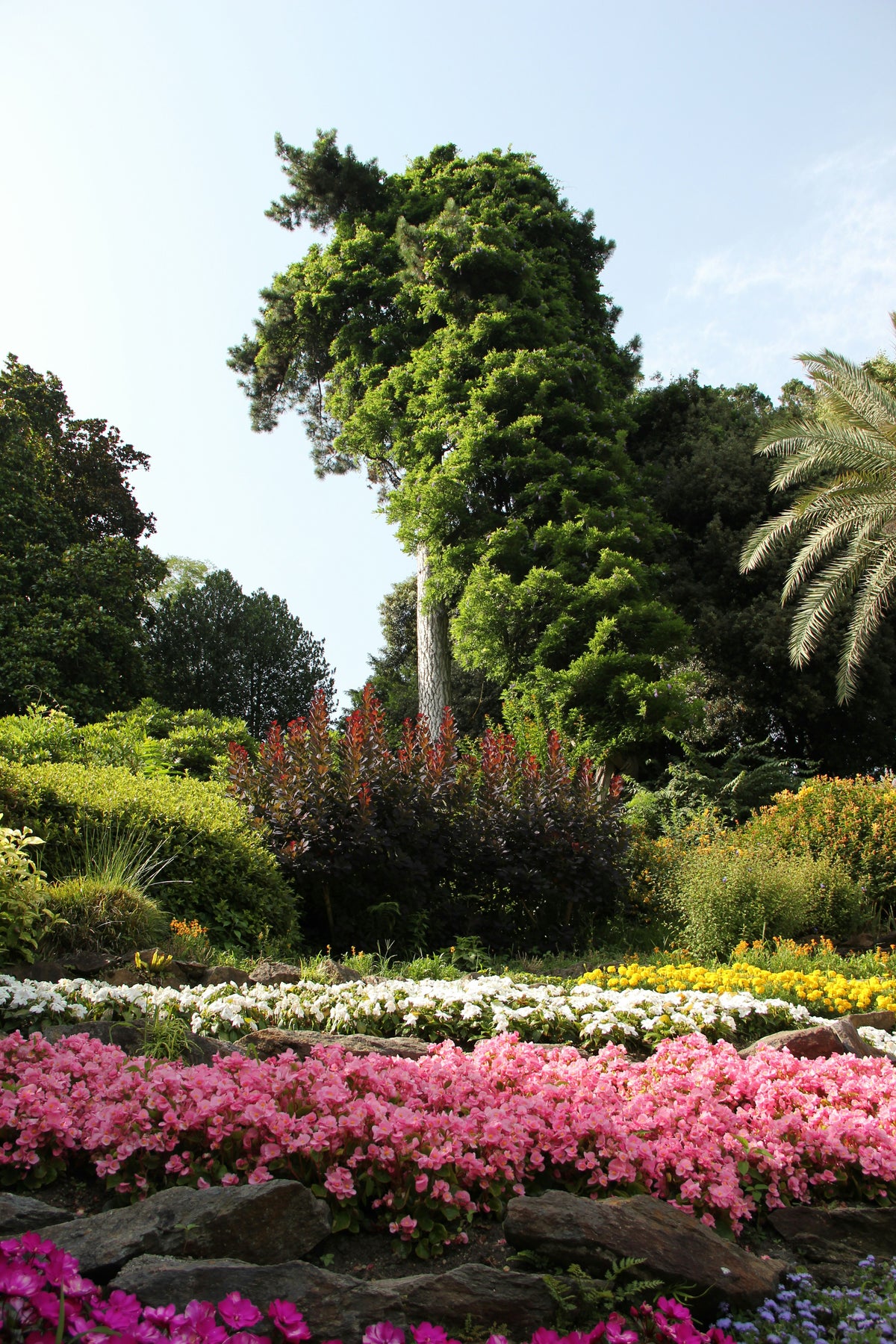 A garden with a giant topiary sculpture and colourful flower beds.