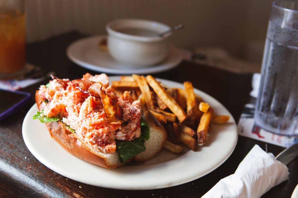 A lobster roll and fries on a plate.