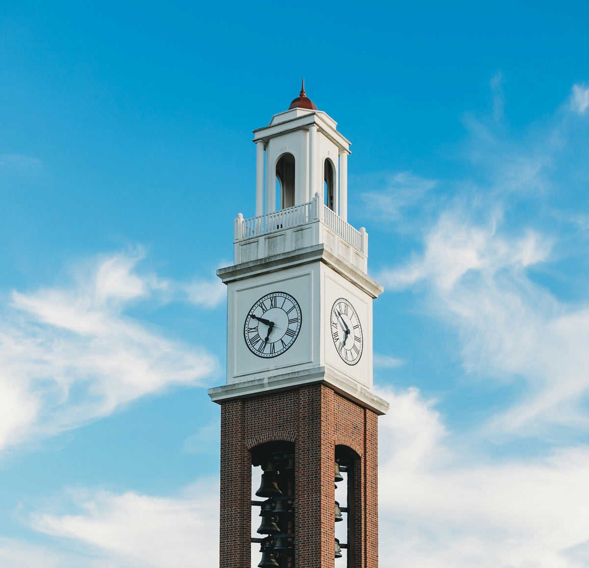 A white clock tower against a blue sky.