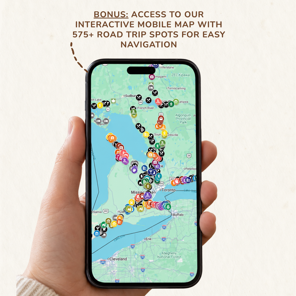 A hand holds a smartphone displaying an interactive mobile map with colorful location pins and navigation spots. Text at the top reads: 'BONUS: ACCESS TO OUR INTERACTIVE MOBILE MAP WITH 575+ ROAD TRIP SPOTS FOR EASY NAVIGATION.