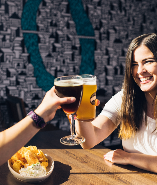 Woman clinking beer with another beer glass.