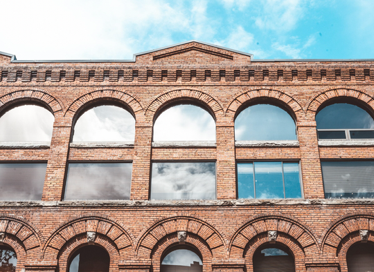 Close up of an old red brick building underneath a vibrant blue sky.