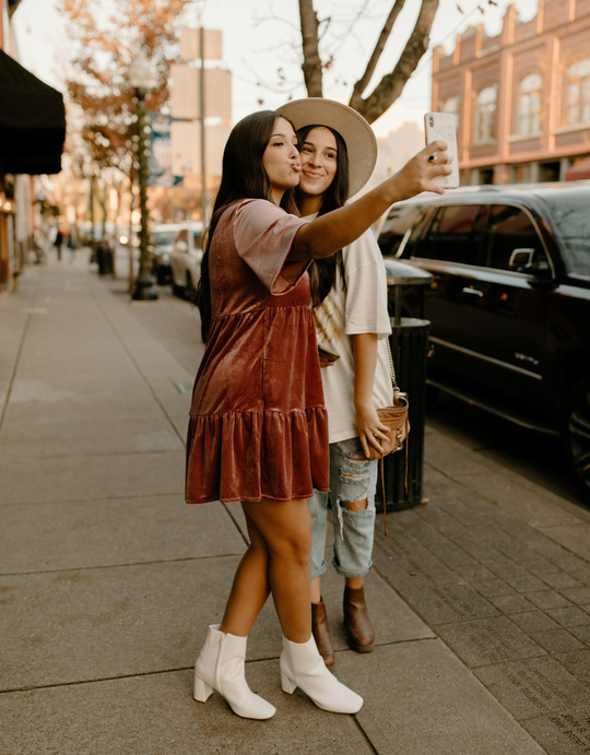 Two friends taking a selfie on a sidewalk.