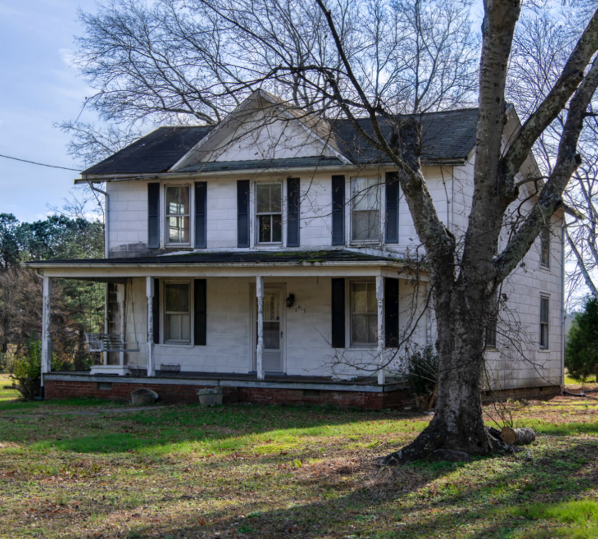 A historic white farmhouse with a wraparound porch.