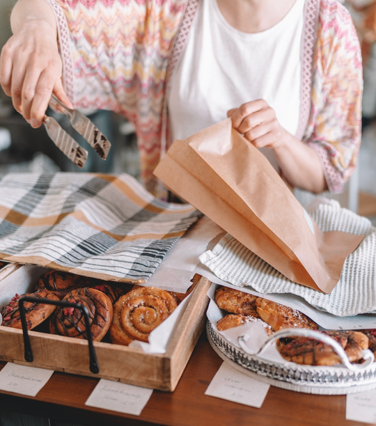 Woman packing up baked goods into a paper bag.