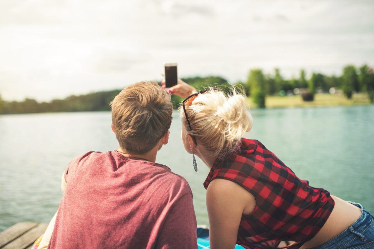 A couple sitting together by a lake.