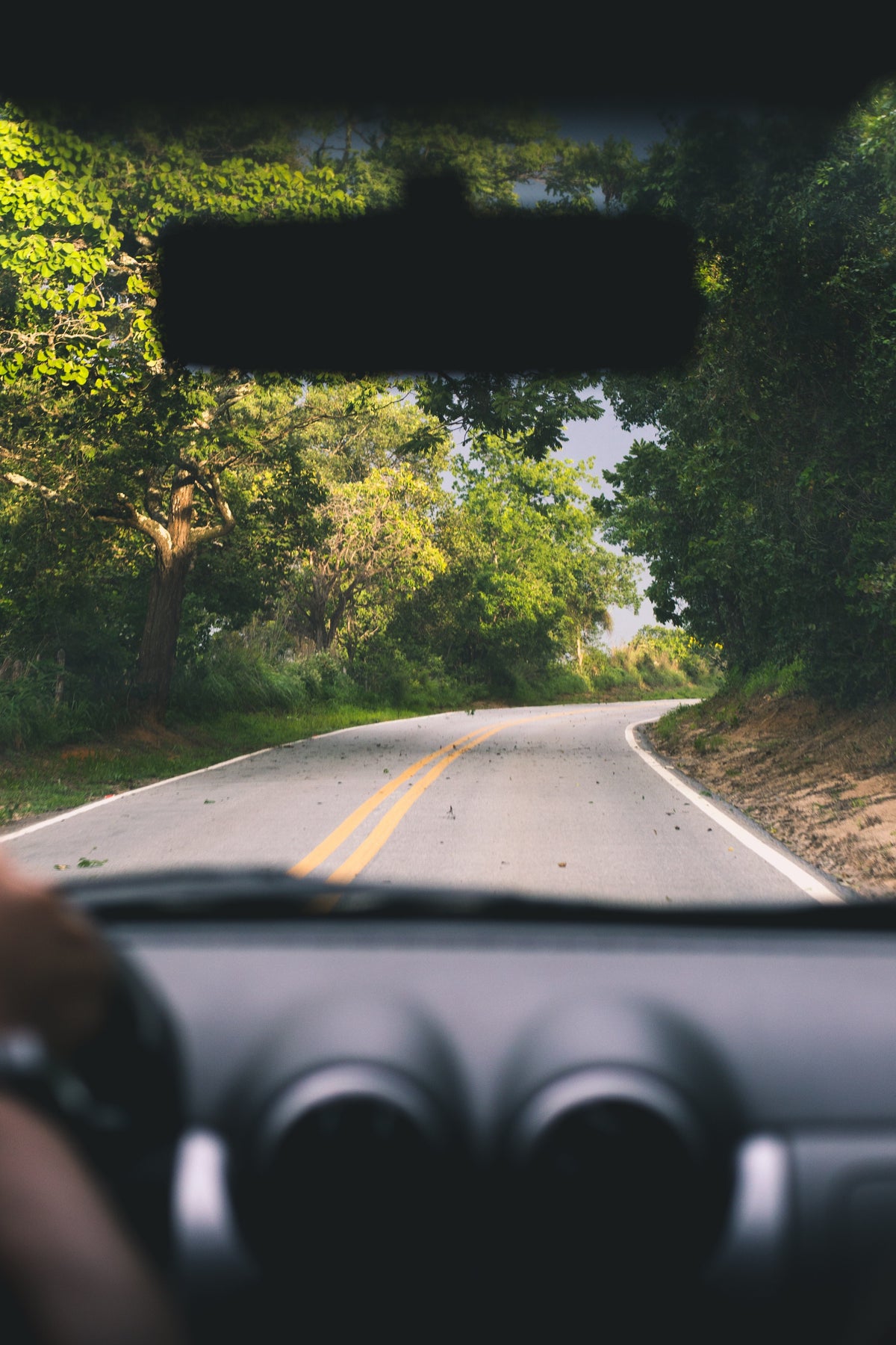 A view of a winding road through the windshield of a car.