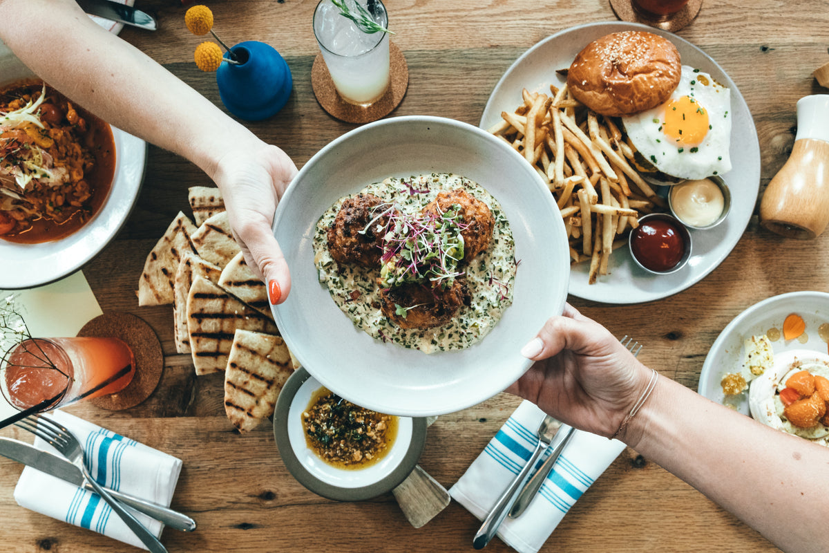 Friends sharing plates of food at a restaurant.