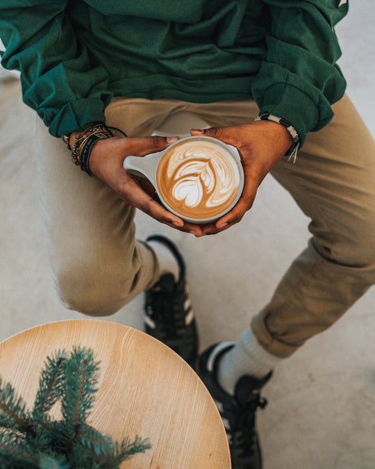 Man holding latte while seated.