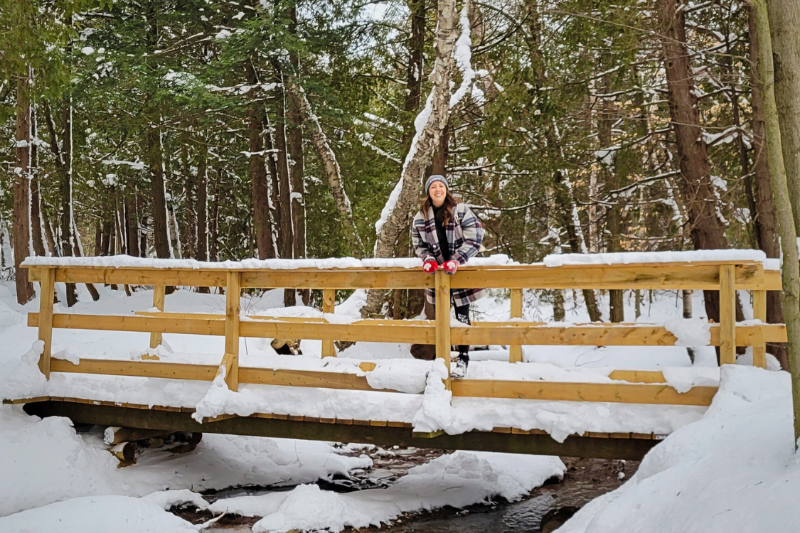 Woman on a snow covered bridge in a winter forest