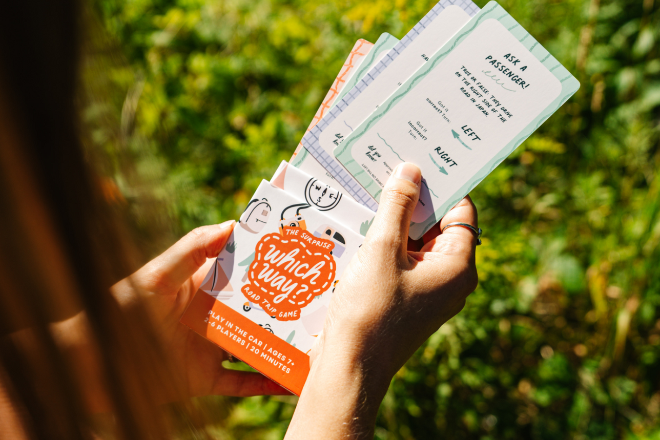 Person holding the Which Way Card game in front of a green background