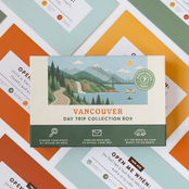 Vancouver Day Trip Box resting on a spread of colourful sealed trip envelopes.