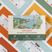 Ontario Getaway Box resting on a spread of colourful sealed trip envelopes.