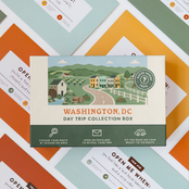 Washington DC Day Trip Box resting on a spread of colourful sealed trip envelopes.
