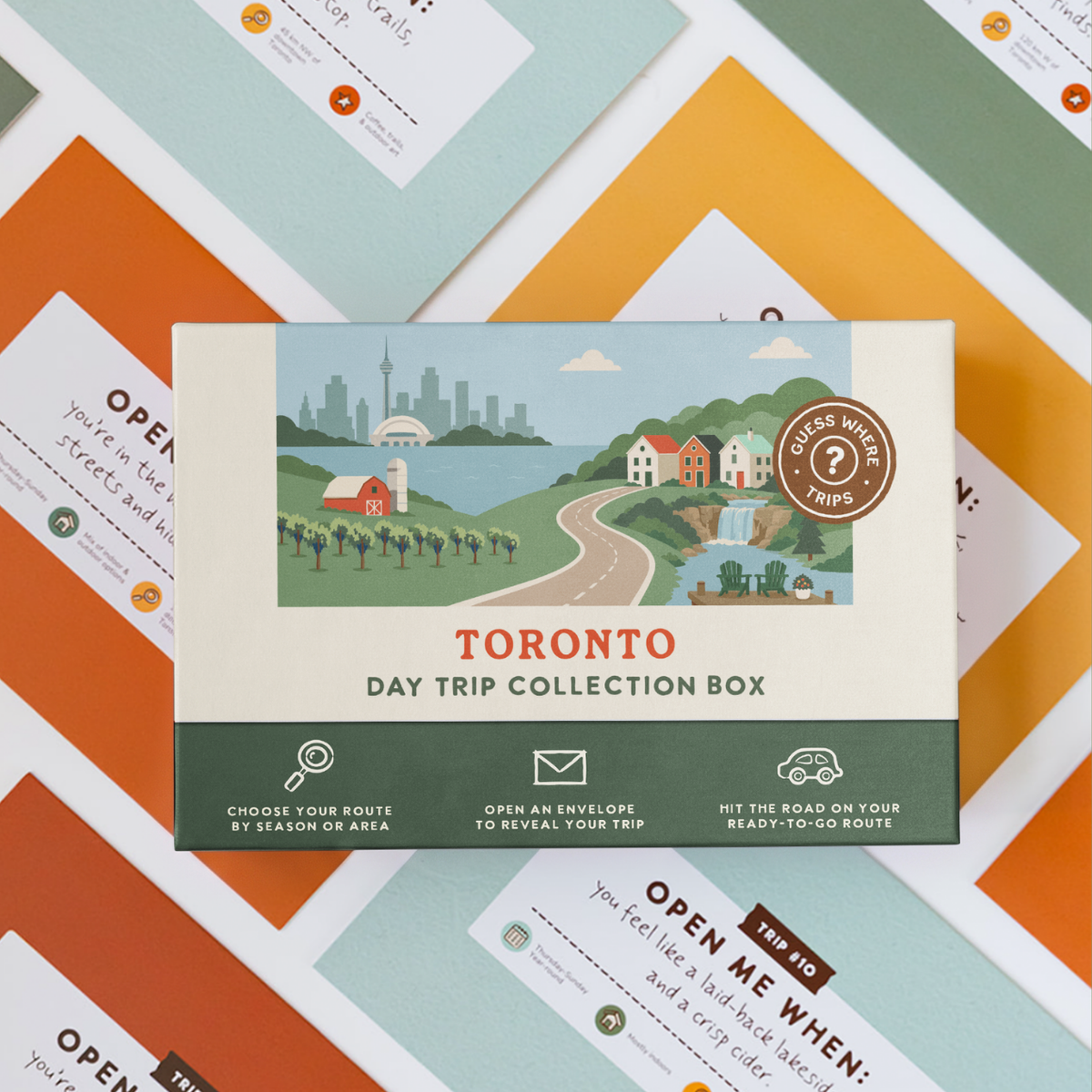 Toronto Day Trip Box resting on a spread of colourful sealed trip envelopes.